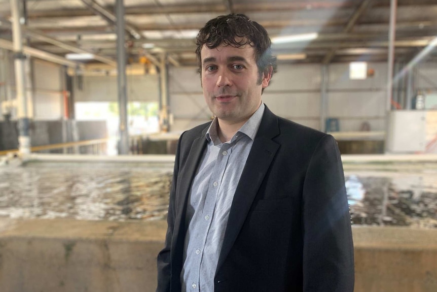 Man in suit standing in front of abalone tank