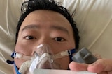 A man on a hospital bed with an oxygen mask on his face.