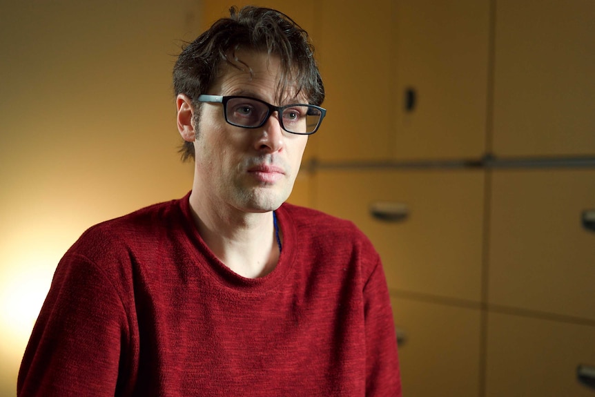 Australian journalist Scott McIntyre, wearing glasses and a red shirt, during an interview.