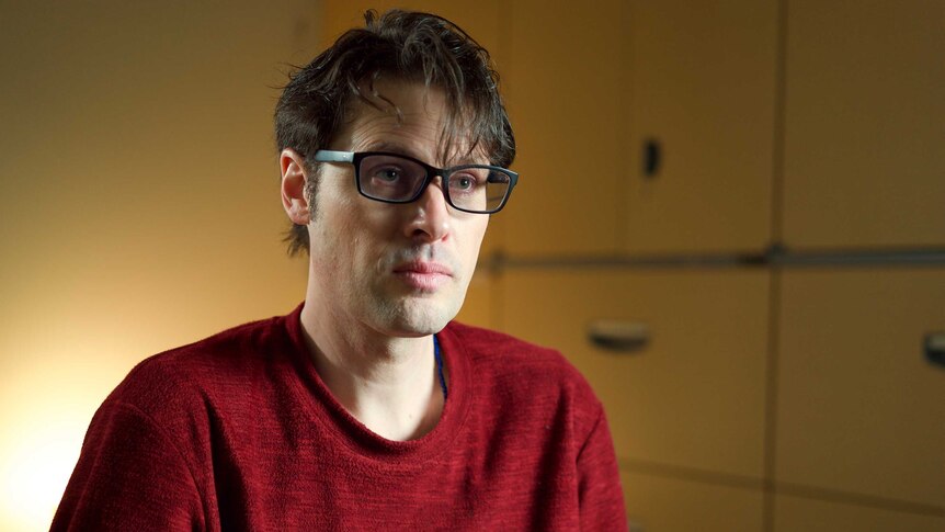 Australian journalist Scott McIntyre, wearing glasses and a red shirt, during an interview.