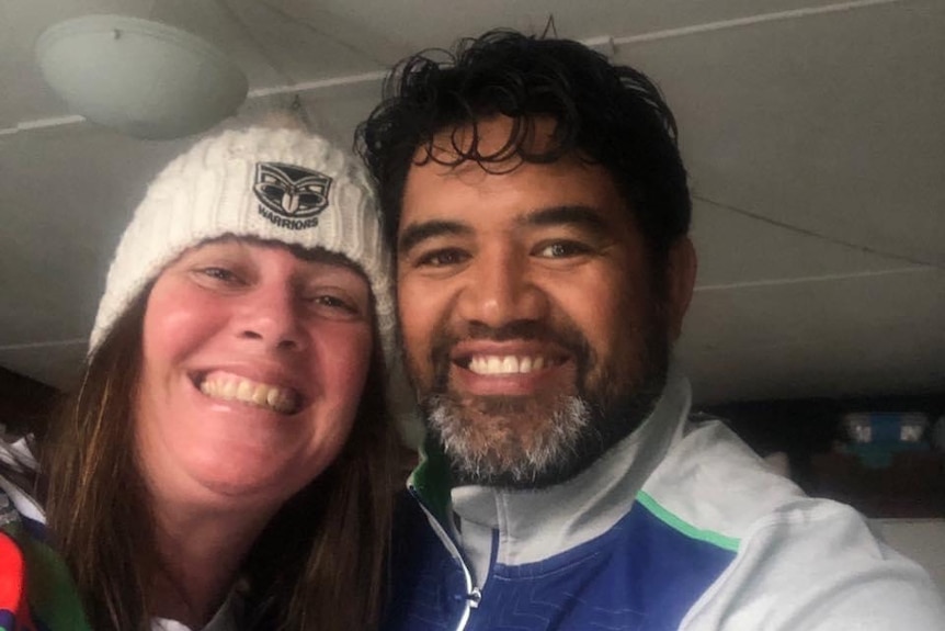 A man and a woman pose for a selfie with Warriors clothing on.