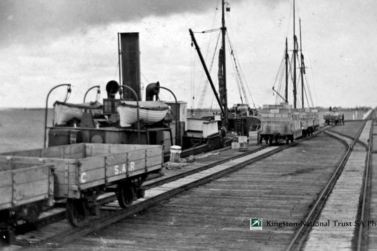 black and white photo of canned rabbit being loaded onto ship from jetty