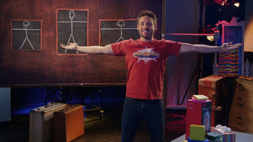 Man holds out arms outstretched, simple stick figures on blackboard behind