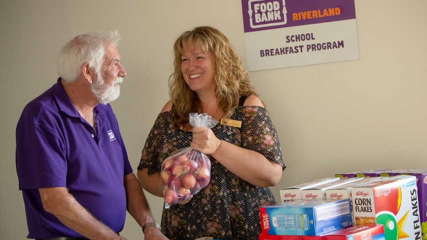 Foodbank Riverland manager Peter Smith with pastoral care worker Karen Knight and a table of breakfast provisions.