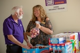 Foodbank Riverland manager Peter Smith with pastoral care worker Karen Knight and a table of breakfast provisions.