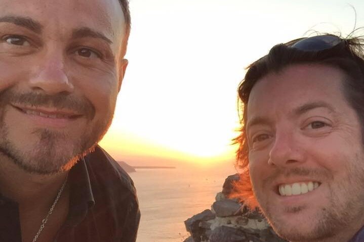 Marco and David Bulmer-Rizzi pose for a selfie photo in front of an ocean.