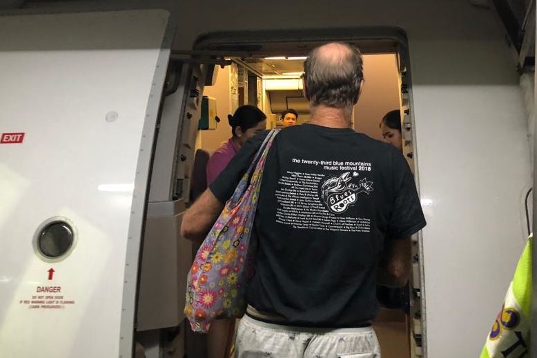 The back of James Ricketson seen as he is boarding a plane