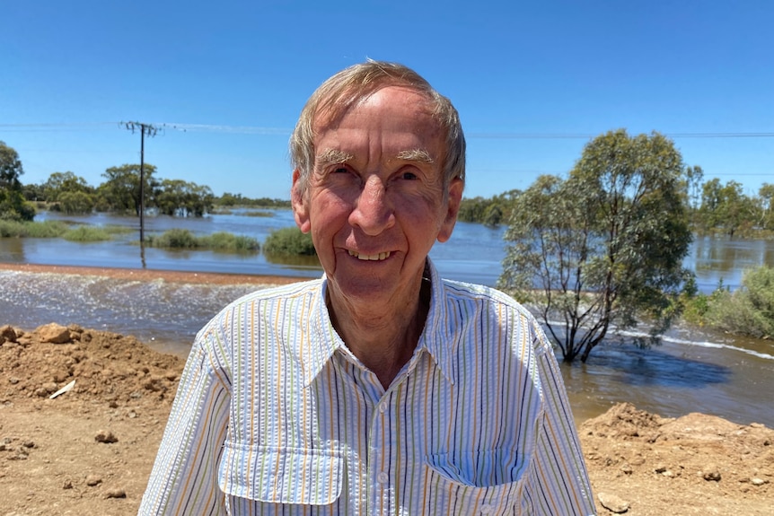 A man looking and smiling, there's rising water and a blue sky behind him
