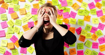 Women standing in front of wall of post-it notes looking overwhelmed.
