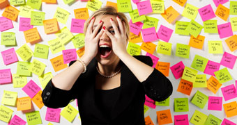 Women standing in front of wall of post-it notes looking overwhelmed.