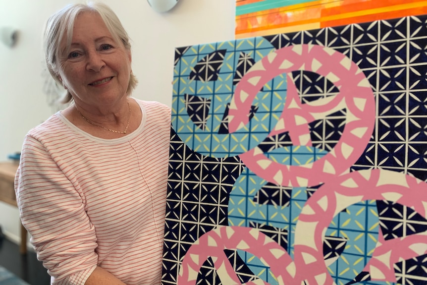 A woman holding a painting of besser bricks.