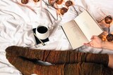 Woman sits on bed with coffee reading a book to depict words that bring people comfort.