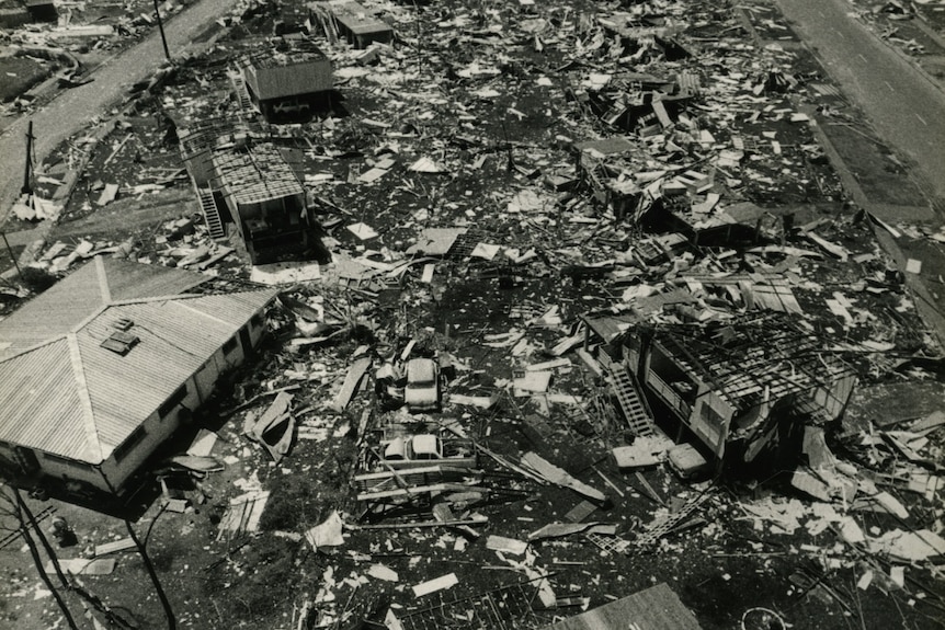Black and white aerial photo shows houses obliterated and building maters covering lawns
