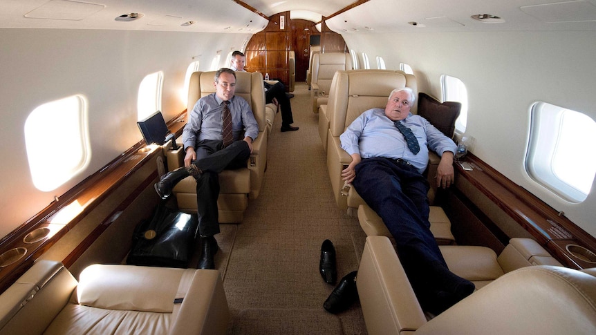 View down the inside of Clive Palmer's jet of Clive Palmer sitting with his shoes off and feet up on one of the chairs.