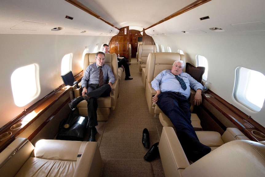 View down the inside of Clive Palmer's jet of Clive Palmer sitting with his shoes off and feet up on one of the chairs.