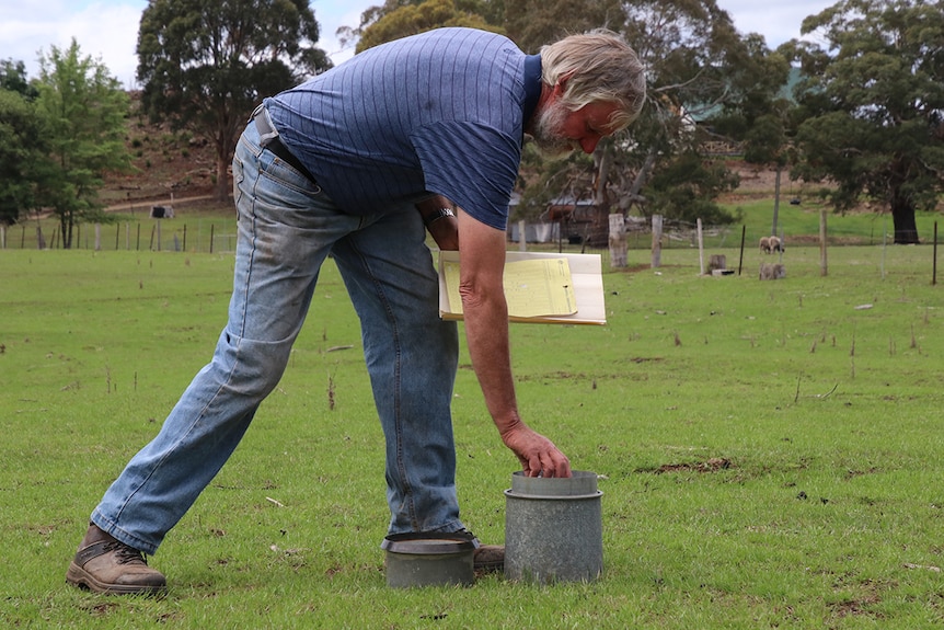 Tasmanian farmer David Amos checking the rain gauge on his Cranbrook property.