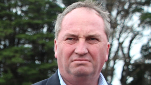 Agriculture Minister Barnaby Joyce standing at a press conference on a farm