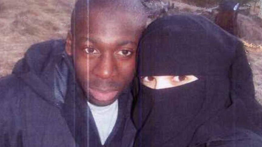 A couple pose, with the woman fully veiled except for her eyes