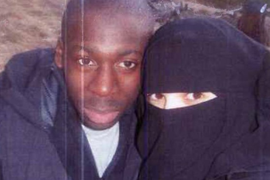 A couple pose, with the woman fully veiled except for her eyes