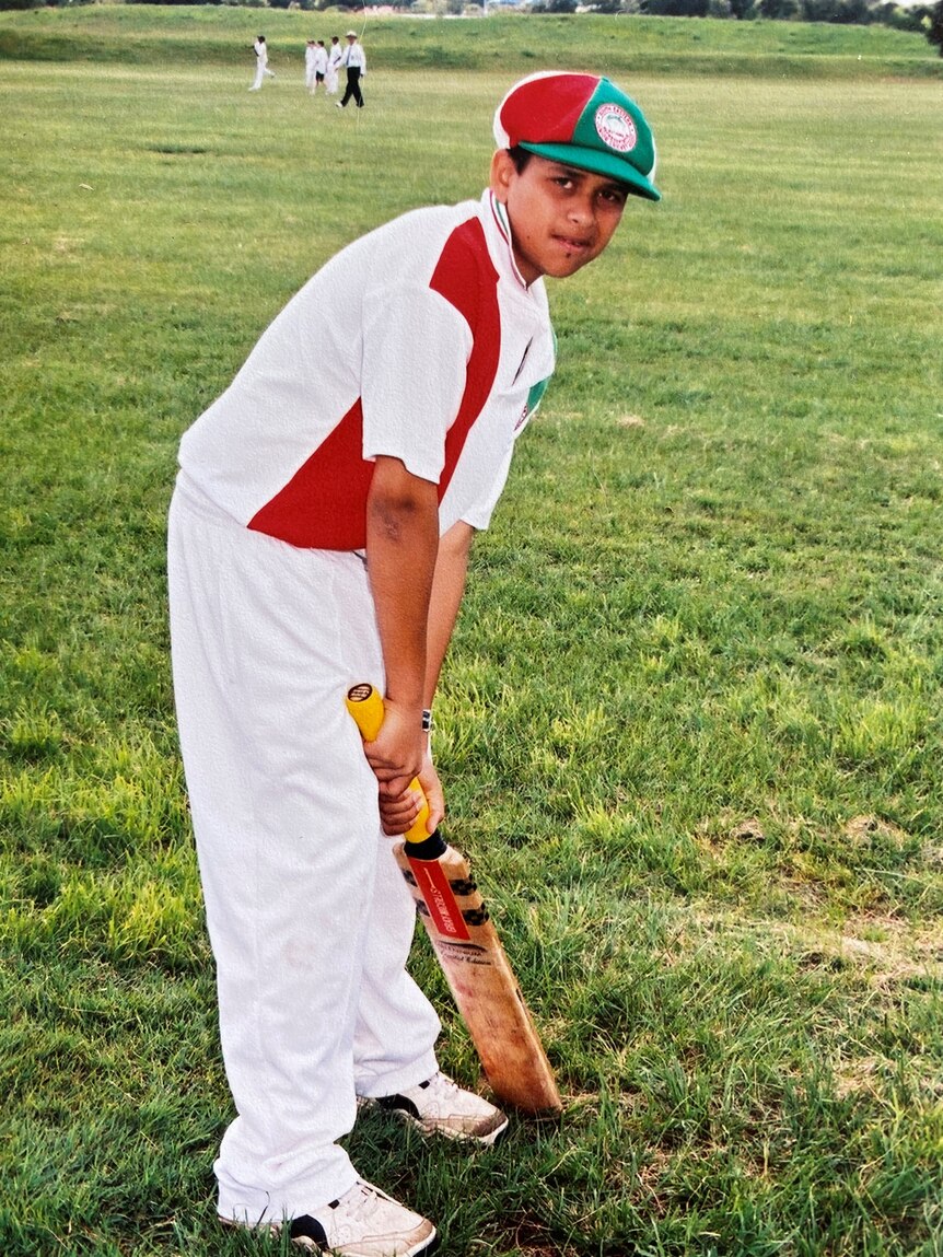 A young Usman Khawaja standing with a bat in his hands