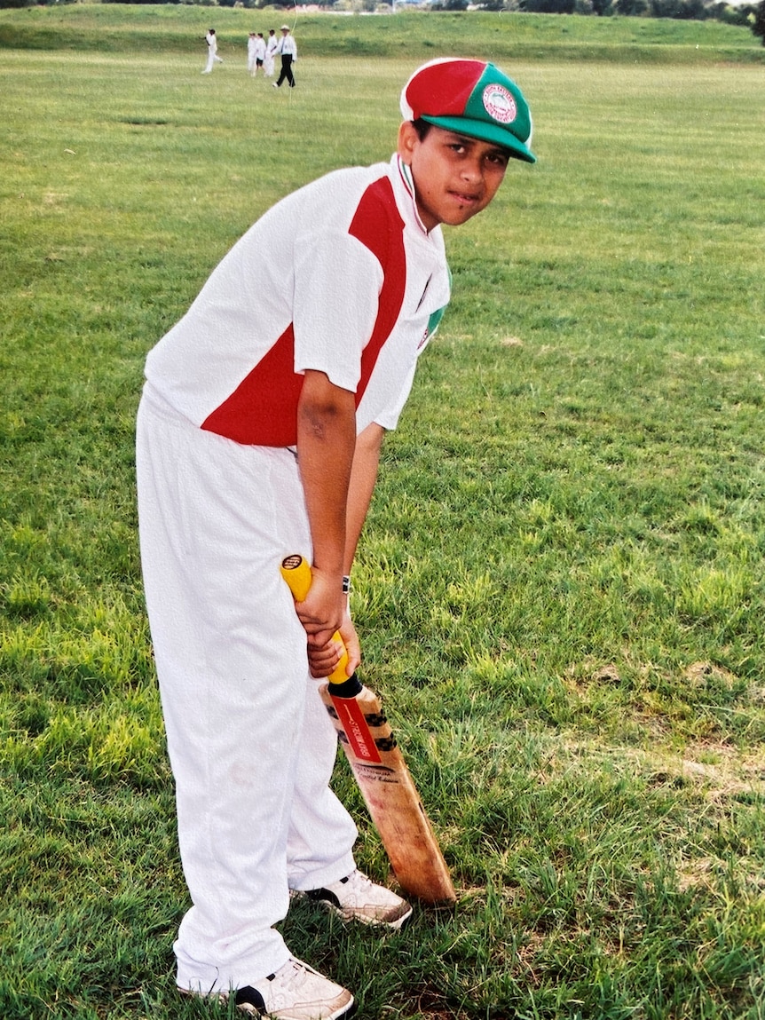 A young Usman Khawaja standing with a bat in his hands