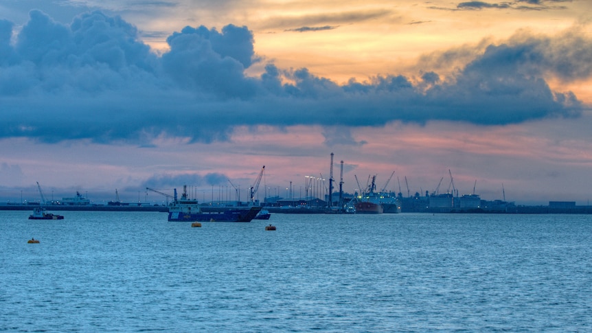 Dramatic harbour view with clouds and industry on the horizon.