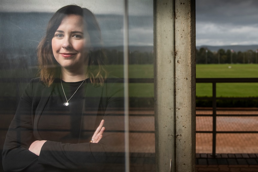 Portrait of Megan Evans in front of glass doors with field in the background.