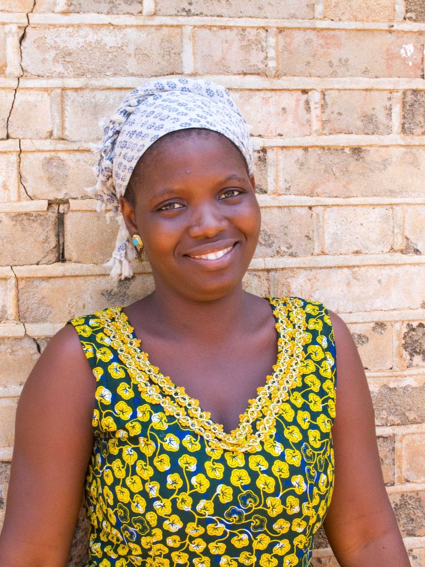 Mariama standing in front of a brick wall smiling.