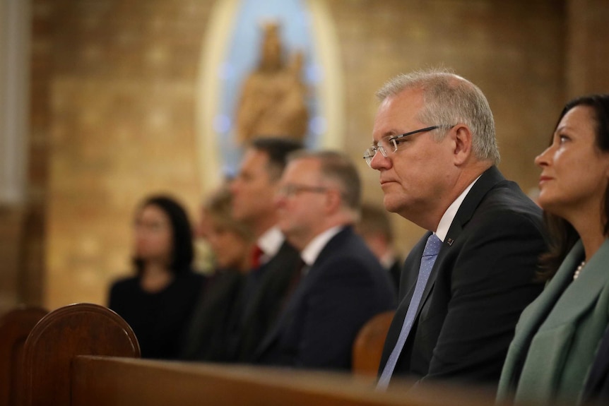 Scott and Jenny Morrison sitting in the front row of a church, with Anthony Albanese and Richard Marles alongside them