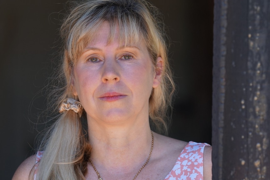 A lady with a sombre expression and side pony looks at the camera