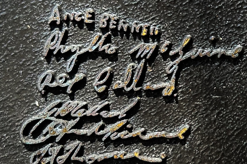 Signatures on a metal plaque, Alice Bennell's is at the top in block letters, the others are in cursive.