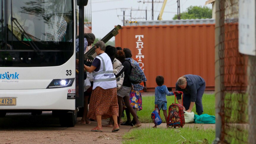 Small children and others get off a bus and gather their bags.