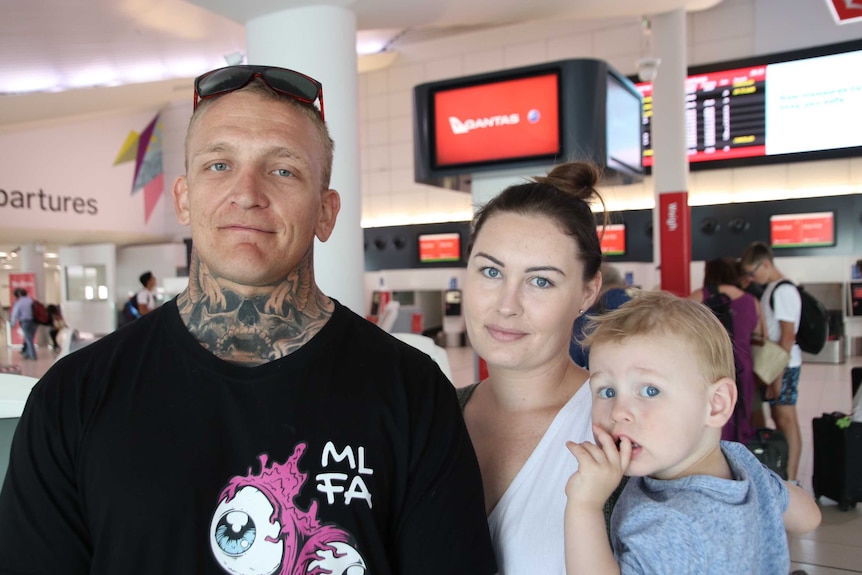 A man and a woman stand posing for a photo holding a little boy in Perth Airport.
