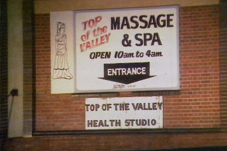 A sign on a brick wall saying Top of the Valley massage parlour.