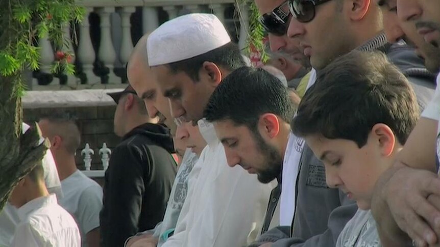 Islamic men bow heads in prayer
