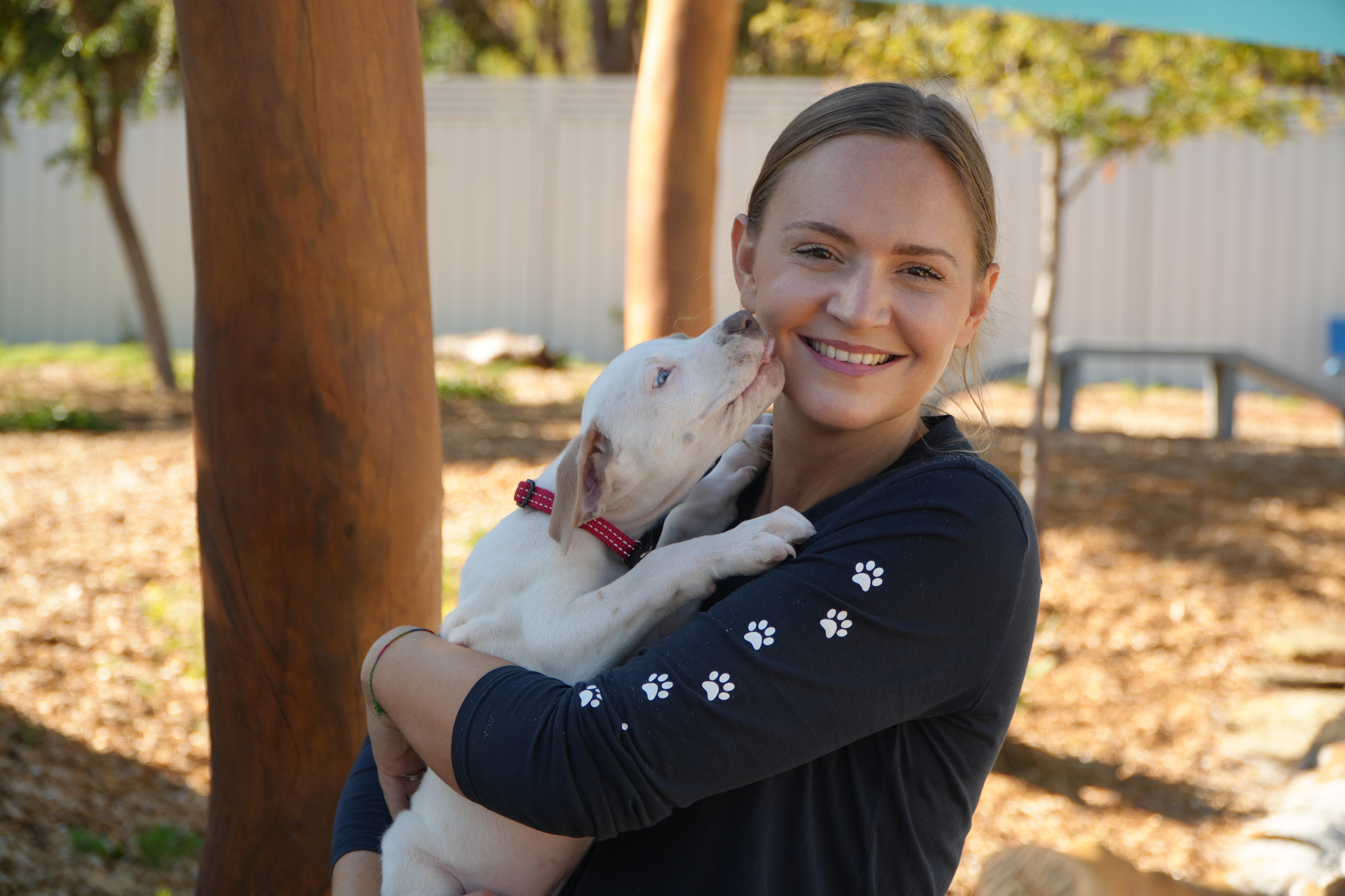 Robyn Slater cuddles a puppy, who licks her face