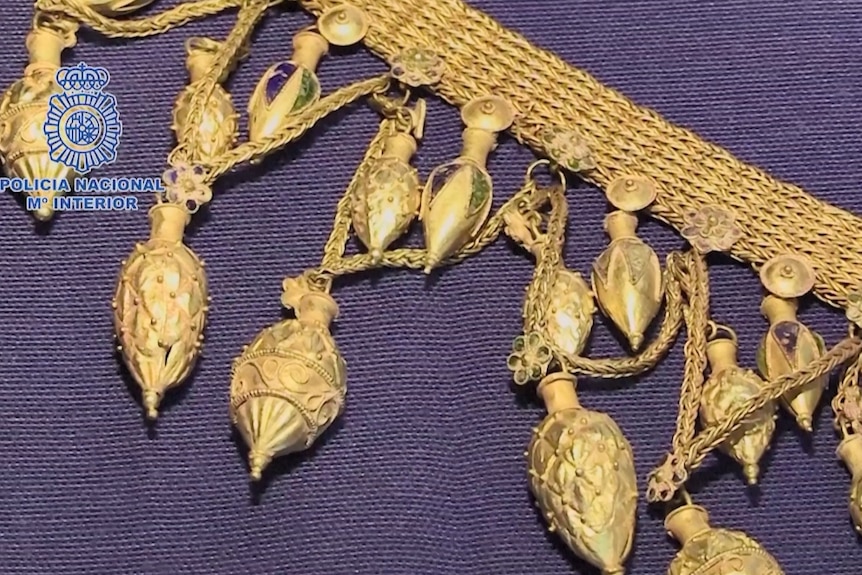 Primer plano de colgantes de oro colgados de un collar de cadena 