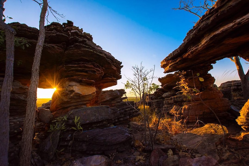 A desert like landscape with large rock formations pictured at dusk.