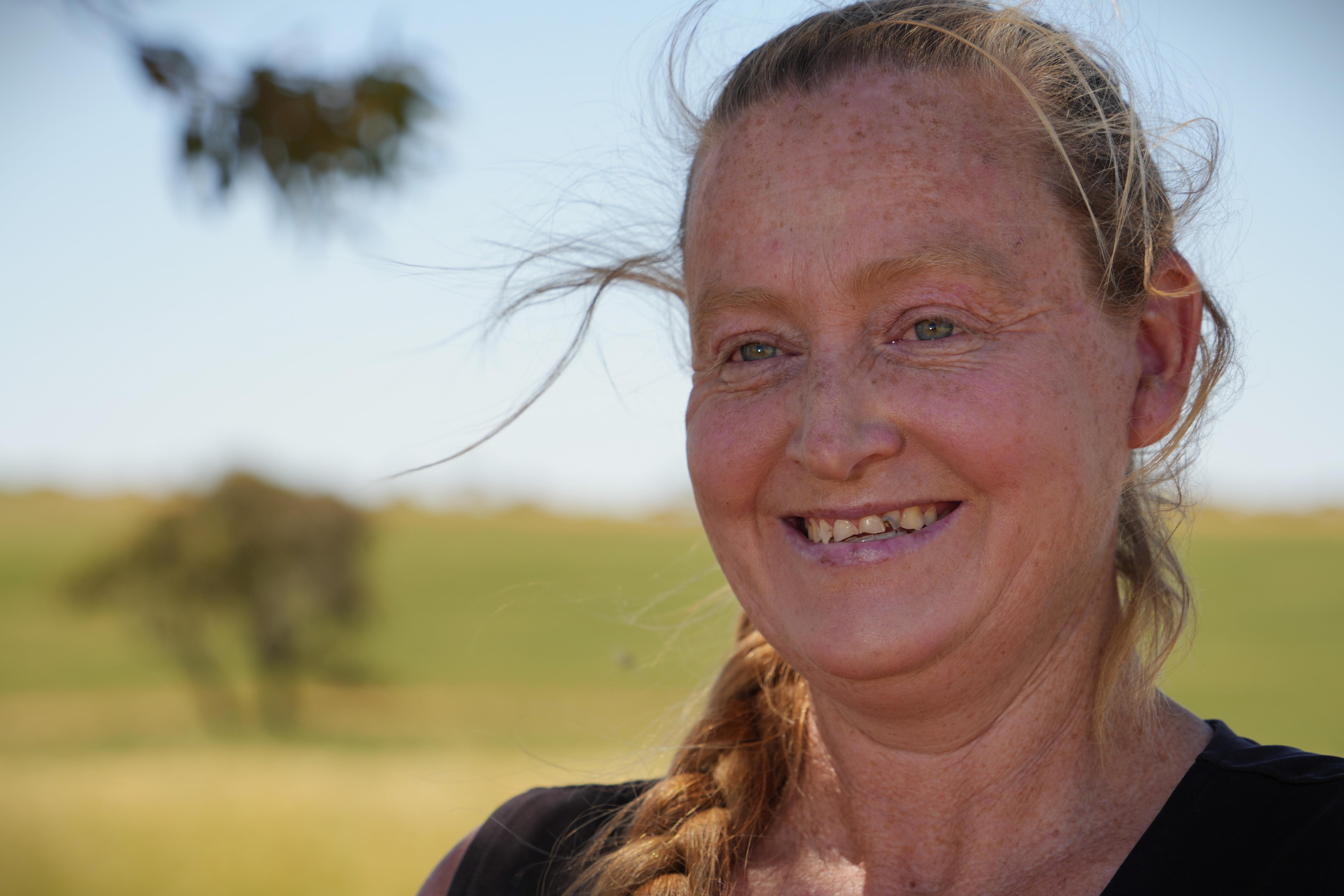 a woman smiles looking into the distance