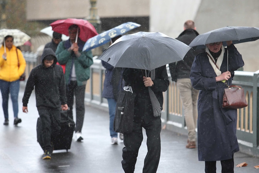 People try to shelter from the rain in Melbourne.