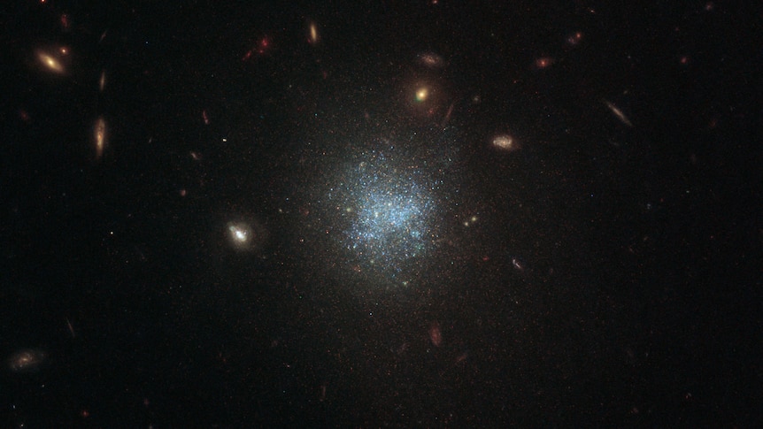 White specks of light are concentrated in the centre of the image, surrounded by the pitch black darkness of outer space. 