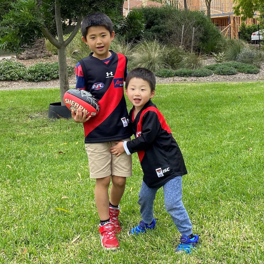 Two boys playing AFL in a park