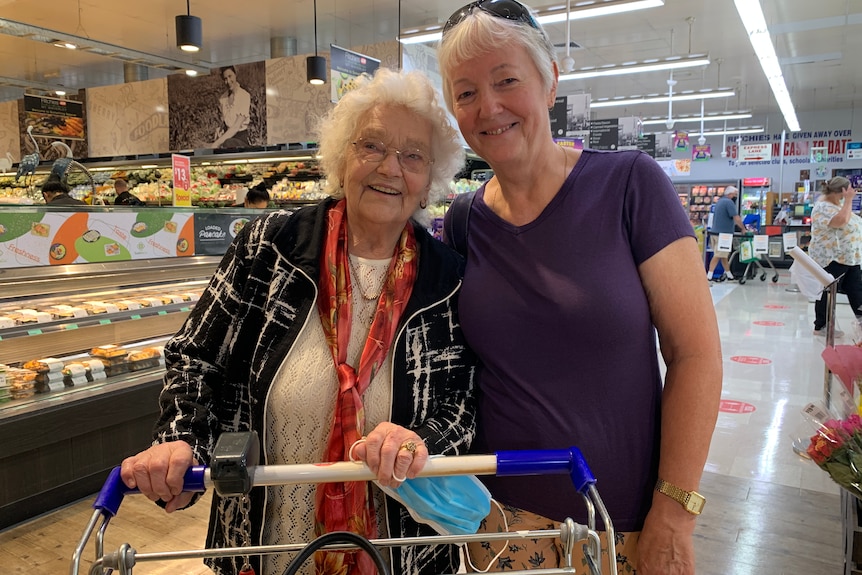 Two women push a shopping trolley at a mall.