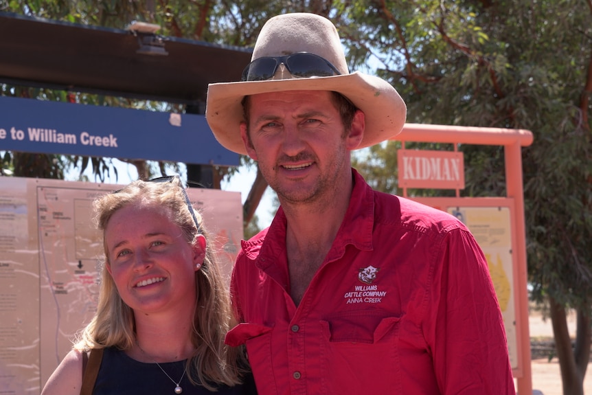A man wearing an Akubra hat and a pink shirt with his hands over the shoulders of a shorter blonde woman