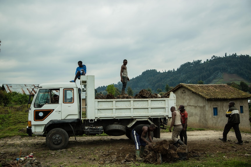 Men sit and work on a large truck.