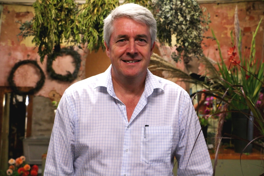 A portrait of a man wearing a white checked button up shirt.