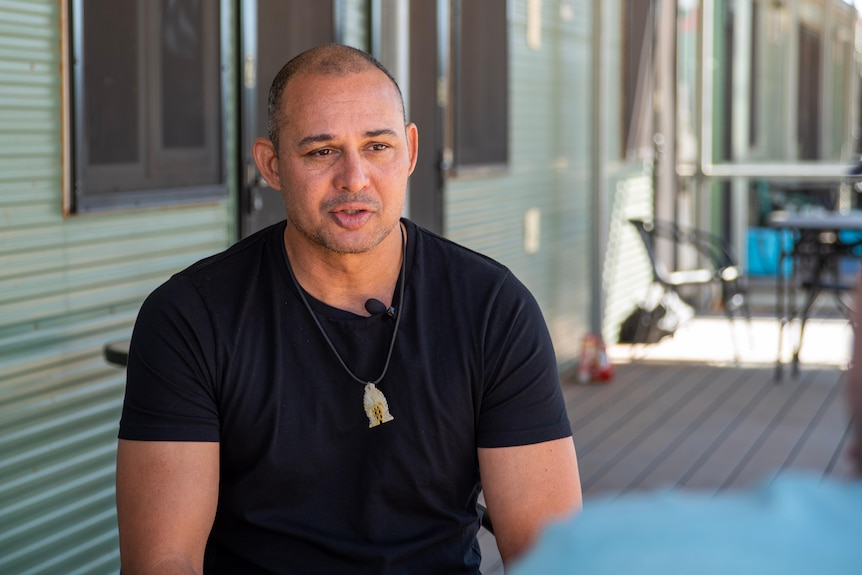 A man wearing a black shirt is being interviewed. 