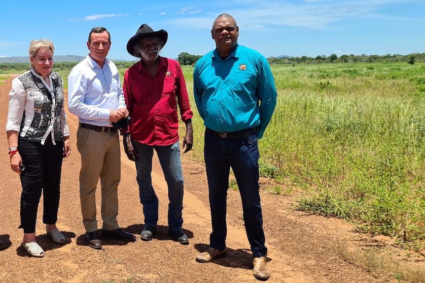 two indigenous men with politicians near a paddock