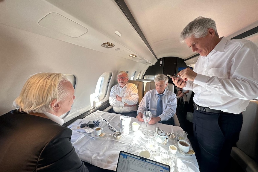 Julian Assange, Kevin Rudd, Barry Pollack and Stephen Smith around a table in a private jet.