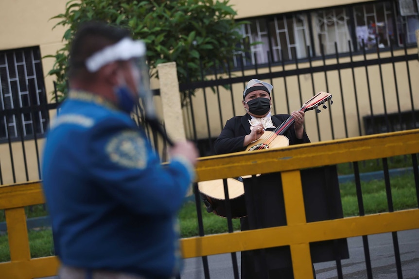 A musician in a mask plays an instrument outside